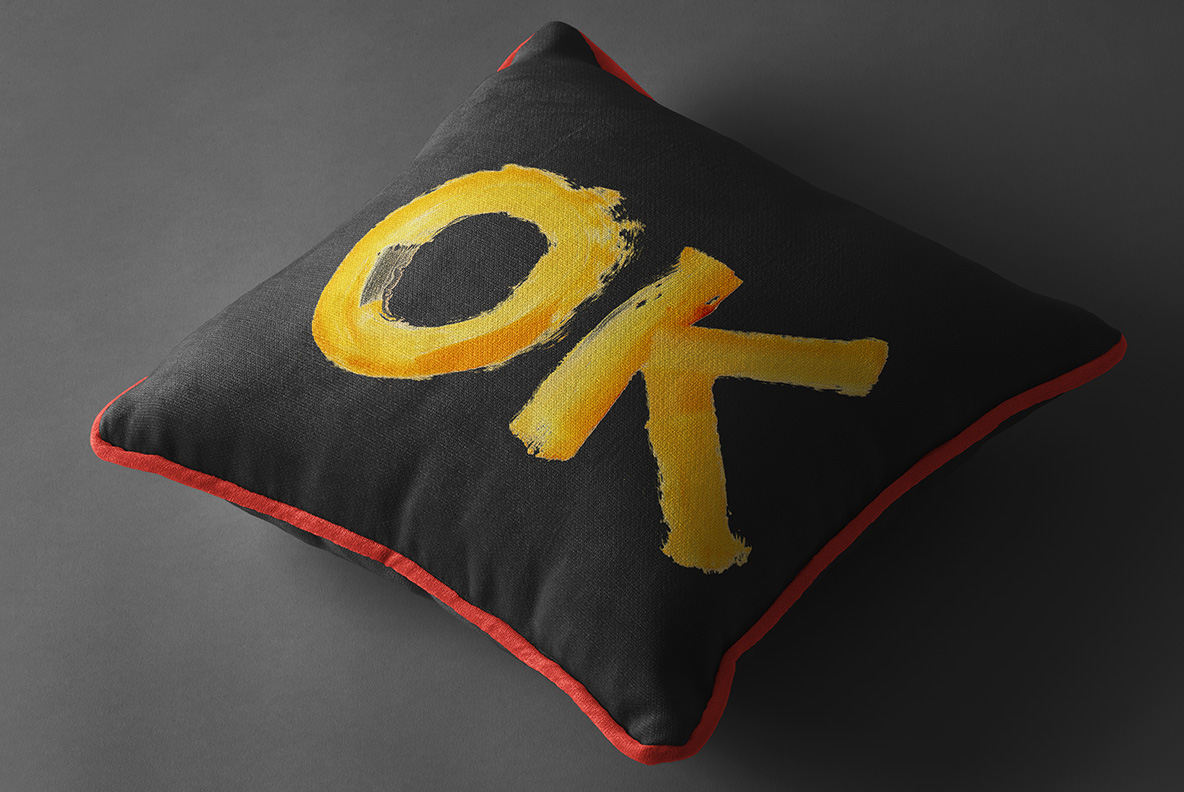 Dark cushion printed with a two-letter word in the Brush Paint Font