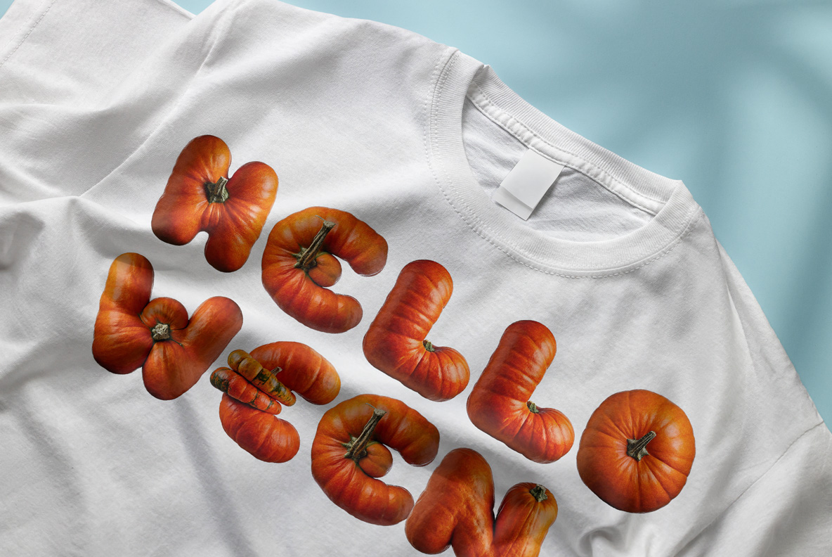 Pumpkin Font – Hello Halloween T-Shirt Mockup Pumpkin Font spelling Hello Halloween in orange pumpkin letters printed diagonally across a white T-shirt.