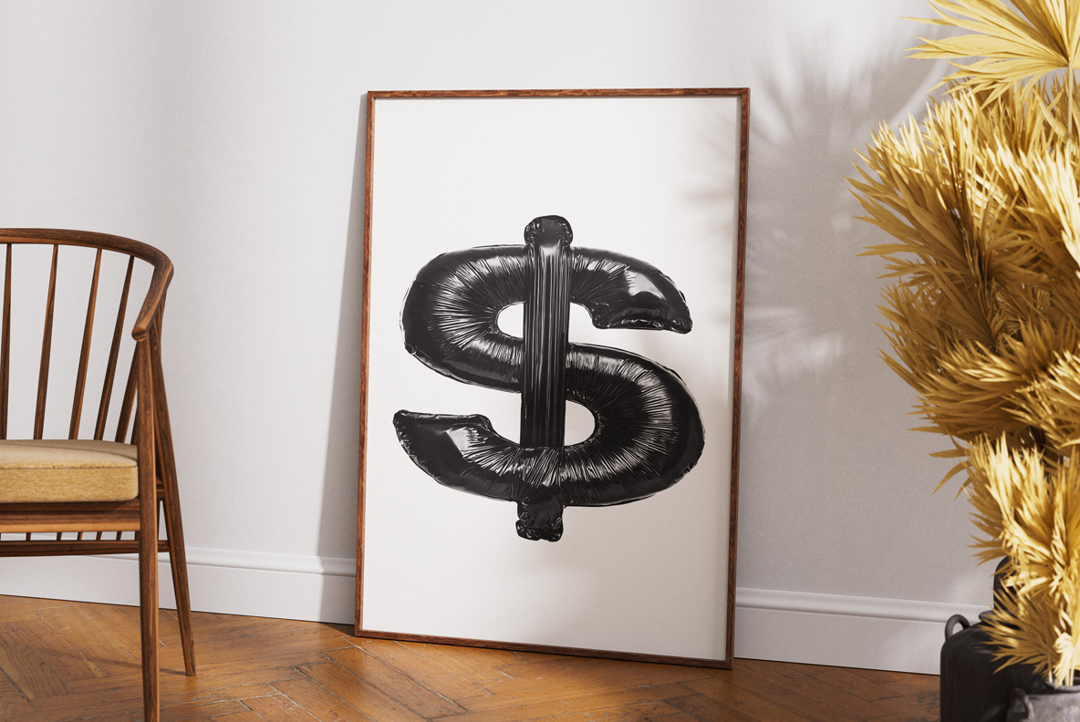 A black plastic dollar sign from Black Bag Bold Font in a wooden frame beside a chair and golden foliage.