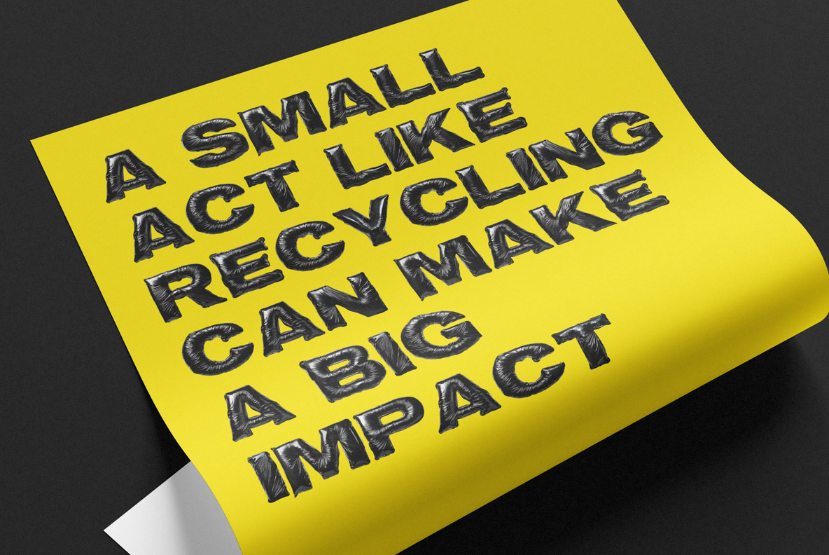 Curled yellow poster reading A small act like recycling can make a big impact in Black Bag Bold Font on a dark surface.