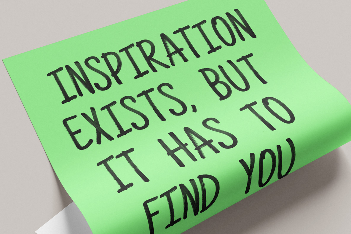 Green curled paper note with a short saying about inspiration in the Paintbrush Flow Font.