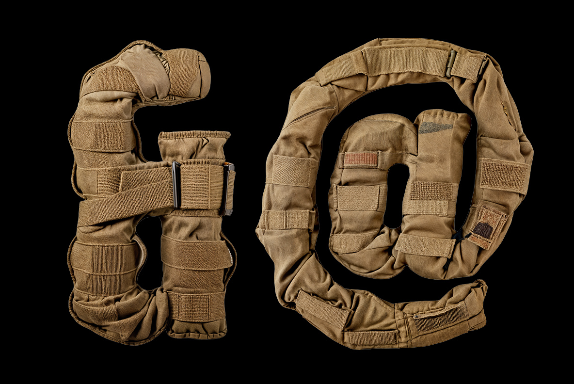 Military Font ampersand and at sign constructed from tan tactical fabric on a black background